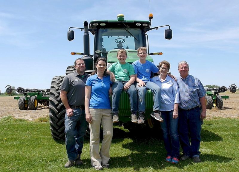 Carrie and her family. Husband Ryan, sons Isaac and Ethan, and parents Kay and Kenny, standing in front of the new John Deere, just two weeks before she used it to plant her first field of soybeans.